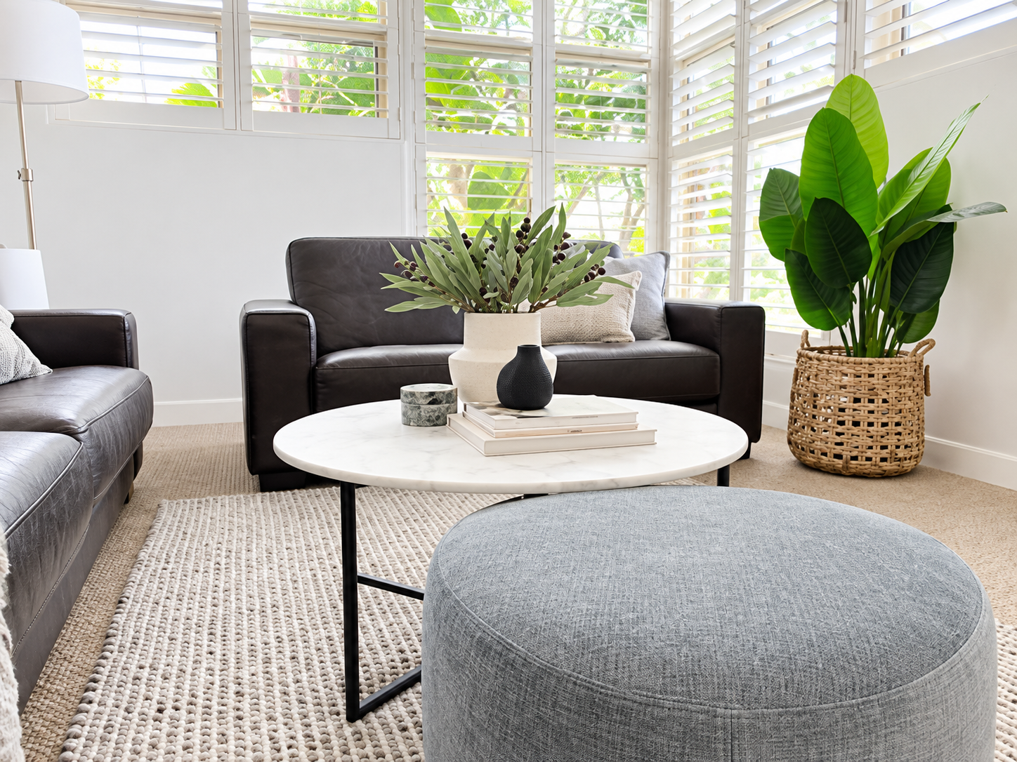Styled living room with leather sofas, marble coffee table and plantation shutters